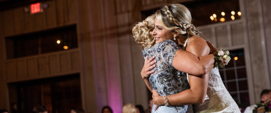 A bride hugging her mom right after the end of their mother-daughter dance at a wedding reception
