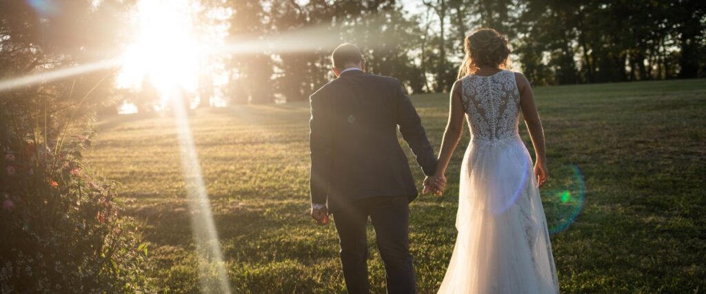 A bride and groom walking together at sunset