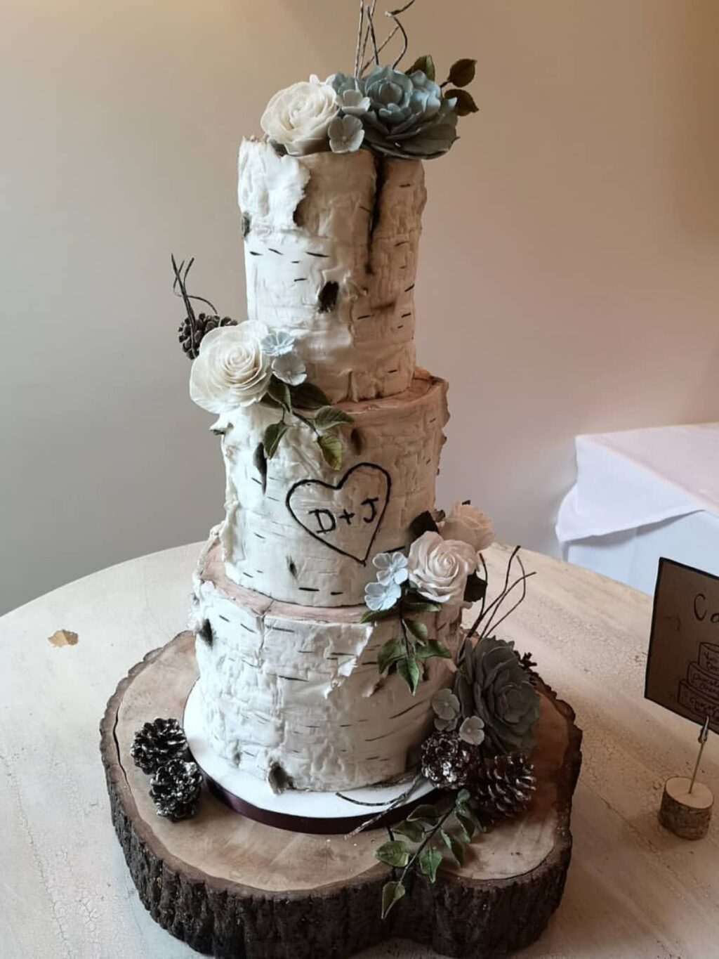 A winter wedding cake that is made to look like birch tree logs with initials carved in it.