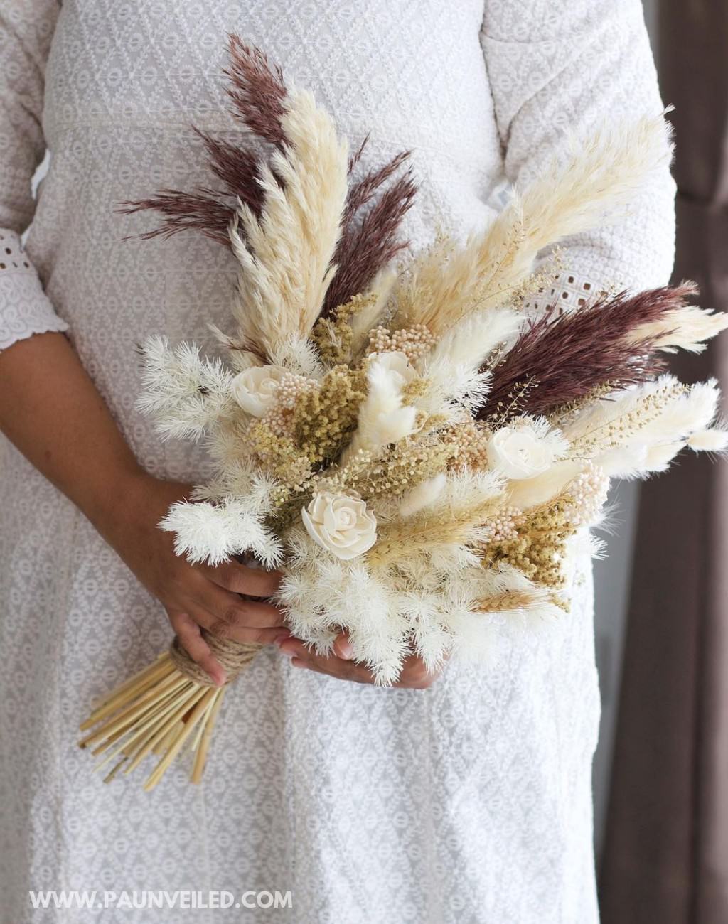 A rustic bridal bouquet made with white, cream, and beige grasses