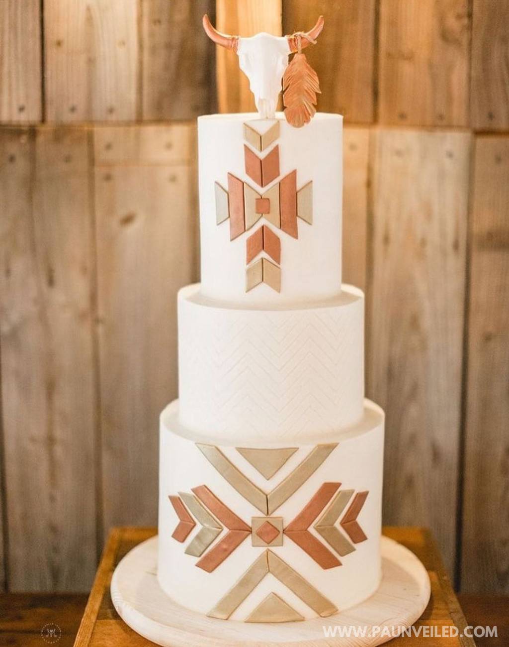 A 3-tier country-wester rustic wedding cake with white frosting and a steer skull cake topper