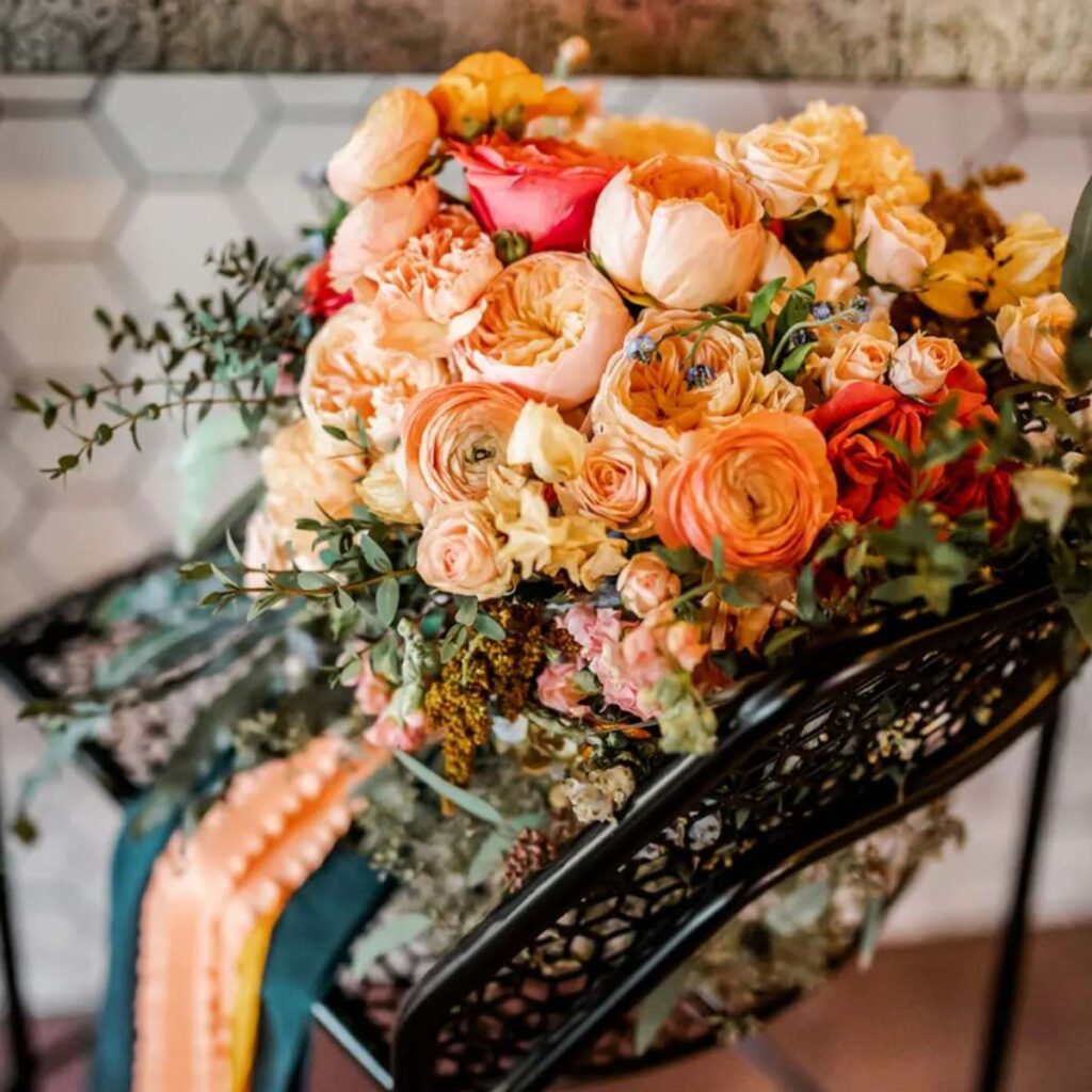 A close up detail photo of a bridal bouquet with orange, yellow, and pink flowers
