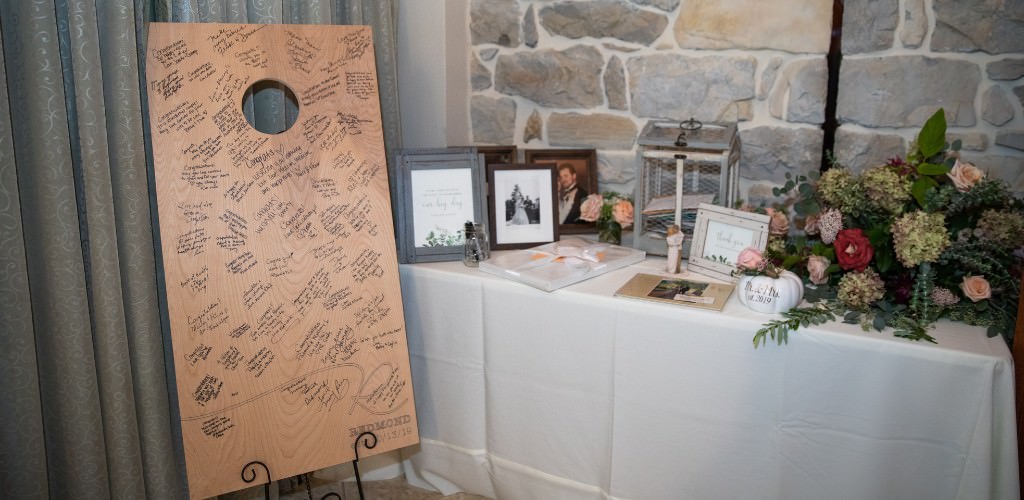 A cornhole game being used as the wedding guest book because it is the couple's favorite yard game.