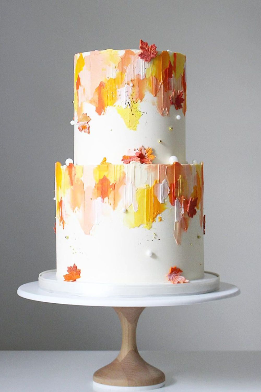 A modern two-tier wedding cake with white orange and yellow