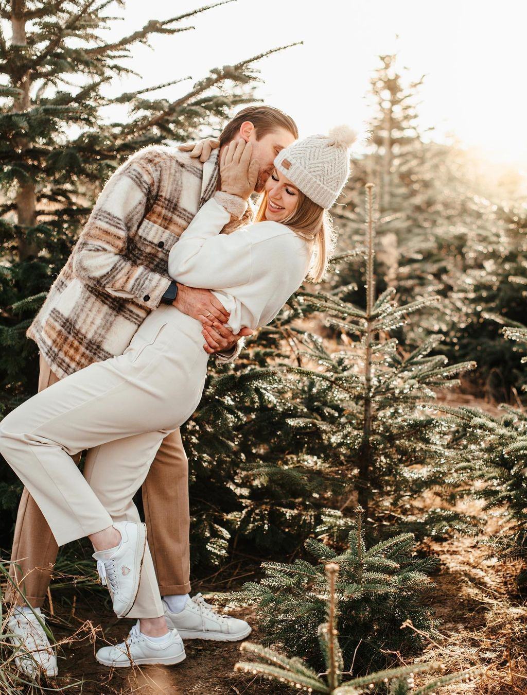 A man kissing a woman on the cheek as they pose in the snow for their winter engagement photos