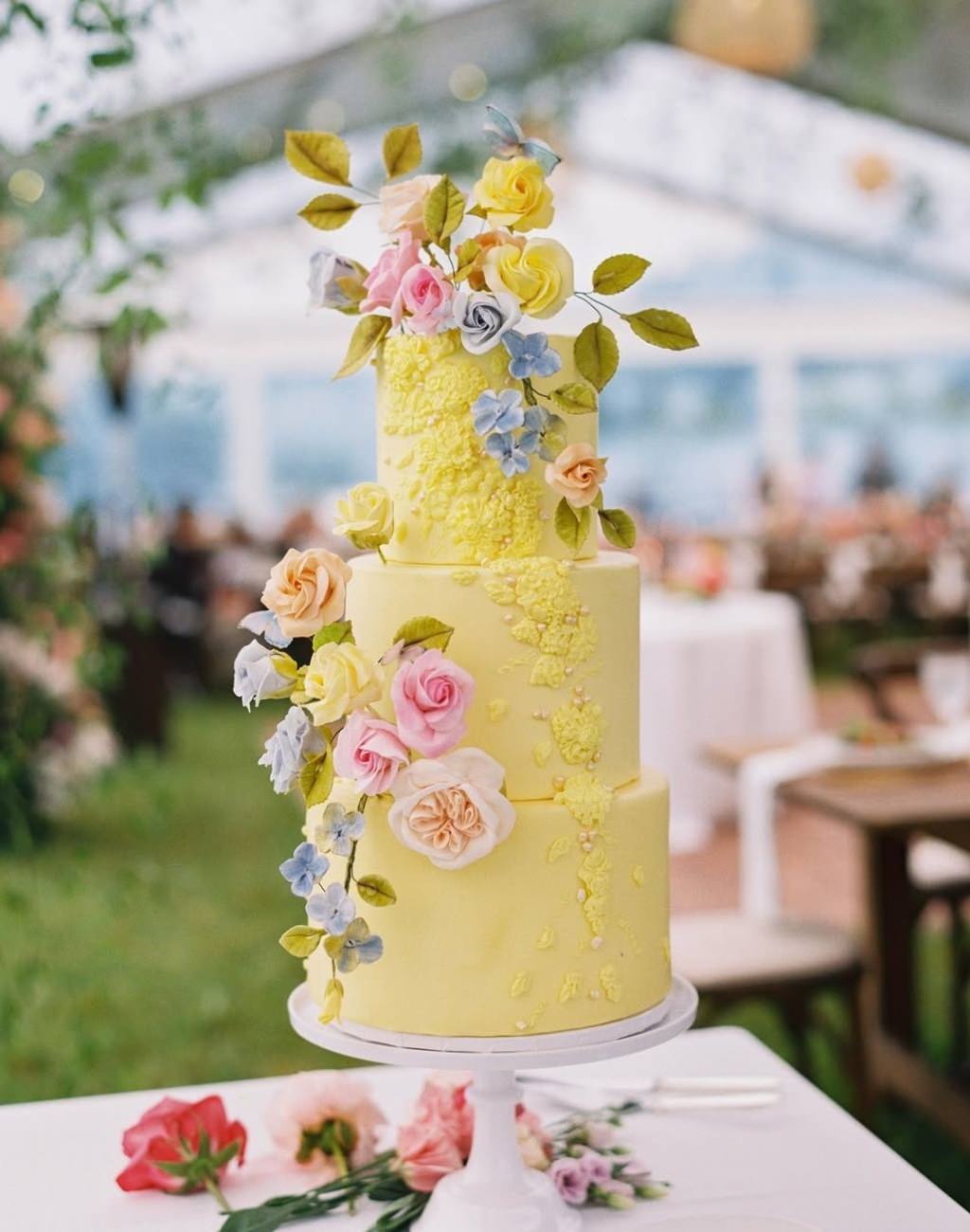 A pretty yellow 3-tier wedding cake with flowers