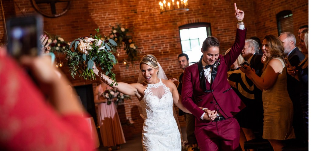 Two brides walking back down the aisle right after they got married