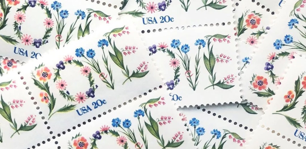 A pile of wedding postage stamps that say love on them. This is for the blog post called hidden wedding expenses