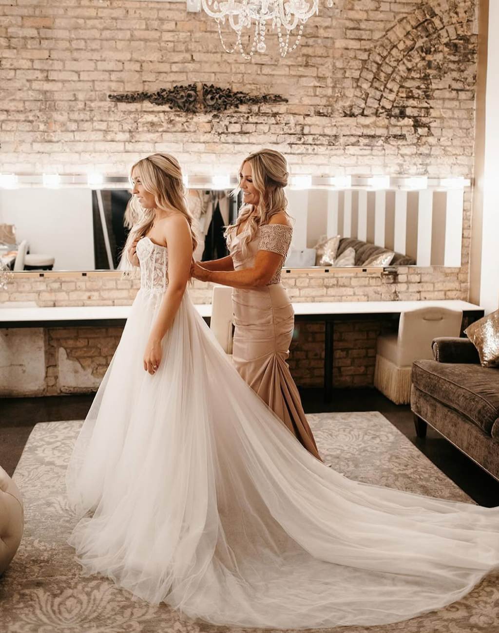 A pretty photo of the bride's mom buttoning up the bride's wedding dress